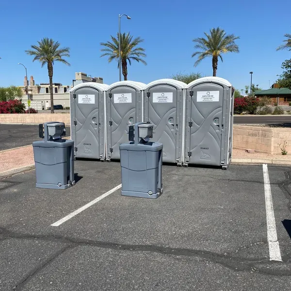 Sanitation One portable toilets and hand wash stations set up with palm trees for a private event